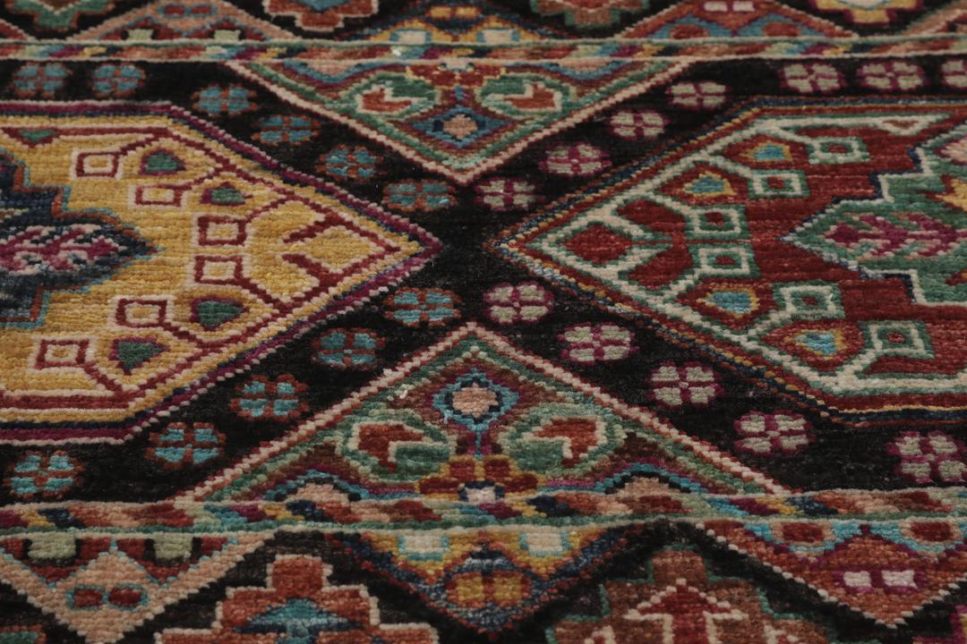 Alfombra afgana anudada a mano con patrones geométricos multicolores sobre fondo negro
