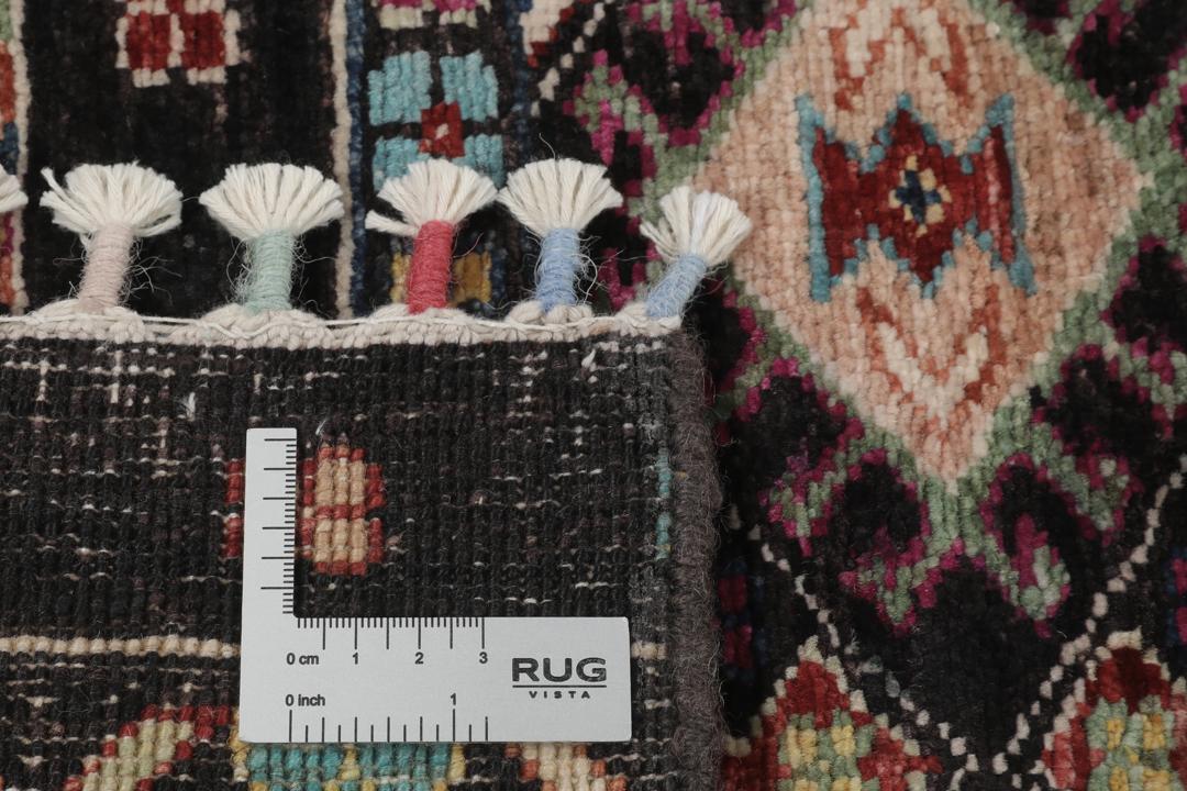 Alfombra afgana anudada a mano con patrones geométricos multicolores sobre fondo negro