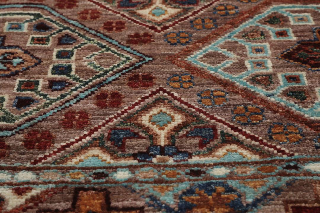 Covor afgan înnodat manual cu modele geometrice în tonuri de maro și albastru.