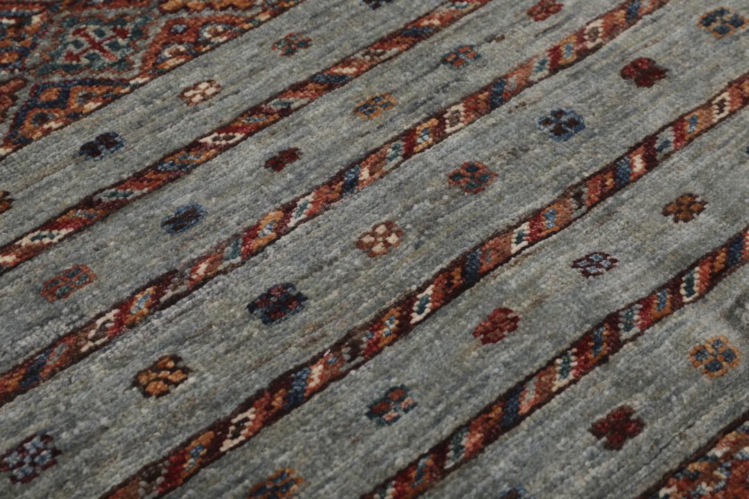 Alfombra afgana anudada a mano en tonos grises y rojos con patrones geométricos