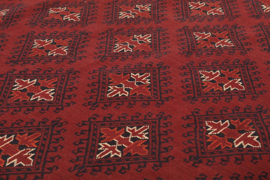 Een handgeknoopt Kunduz-tapijt uit Afghanistan met een donkerrood veld en geometrische patronen.