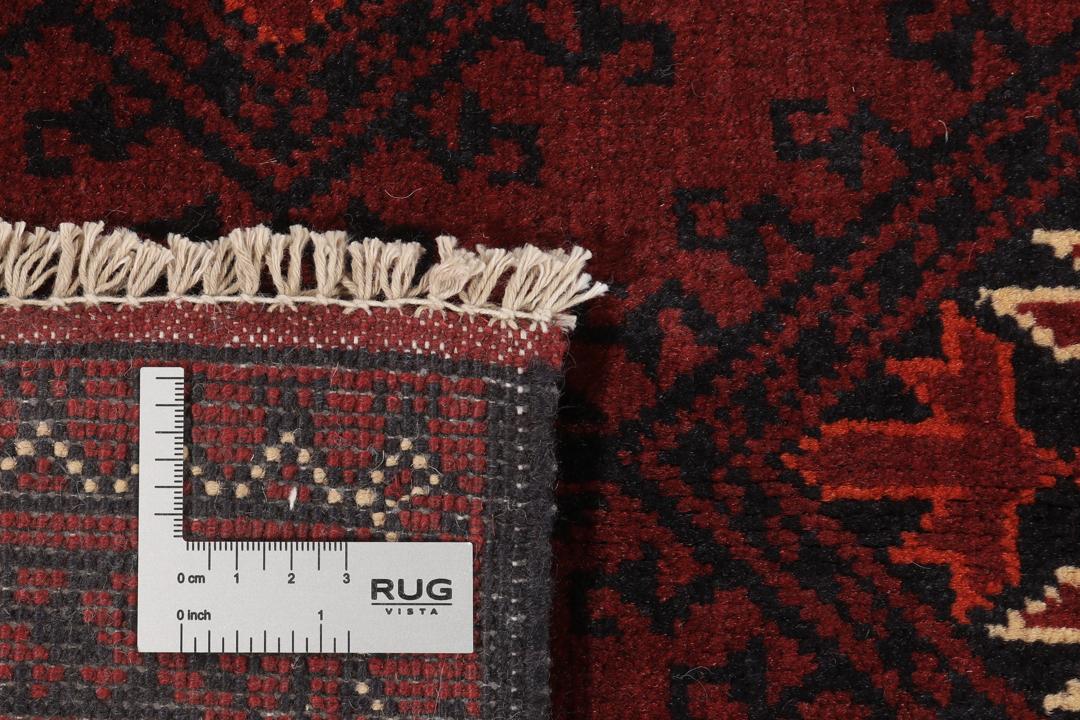 Een handgeknoopt Kunduz-tapijt uit Afghanistan met een donkerrood veld en geometrische patronen.