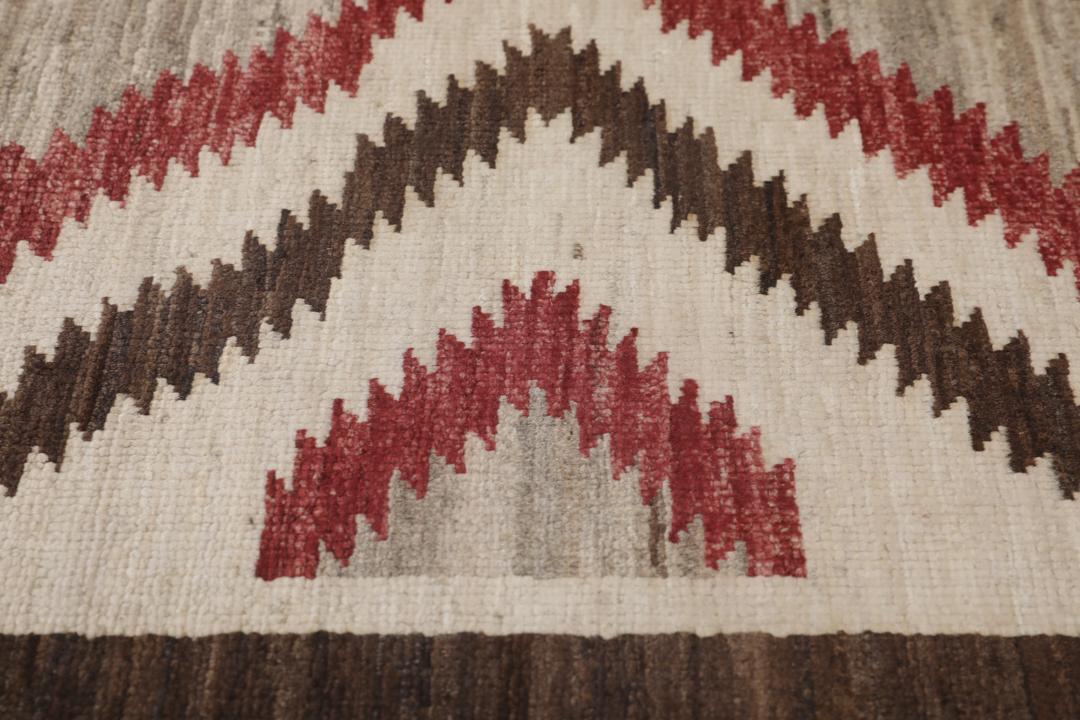Een handgeknoopte Afghaanse loper met een gedurfd geometrisch ruitpatroon in rode, bruine en beige tinten.