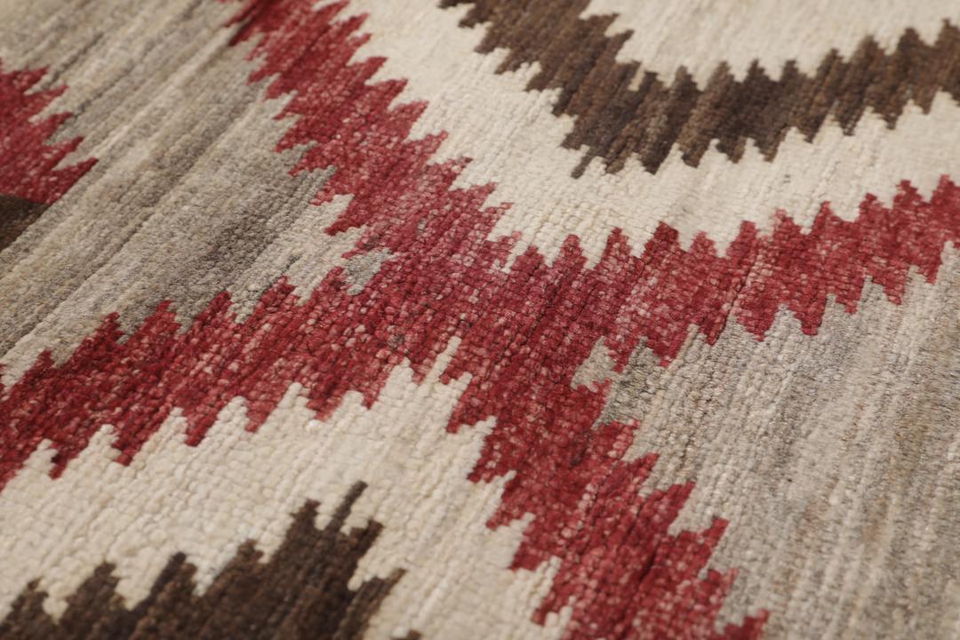 Een handgeknoopte Afghaanse loper met een gedurfd geometrisch ruitpatroon in rode, bruine en beige tinten.