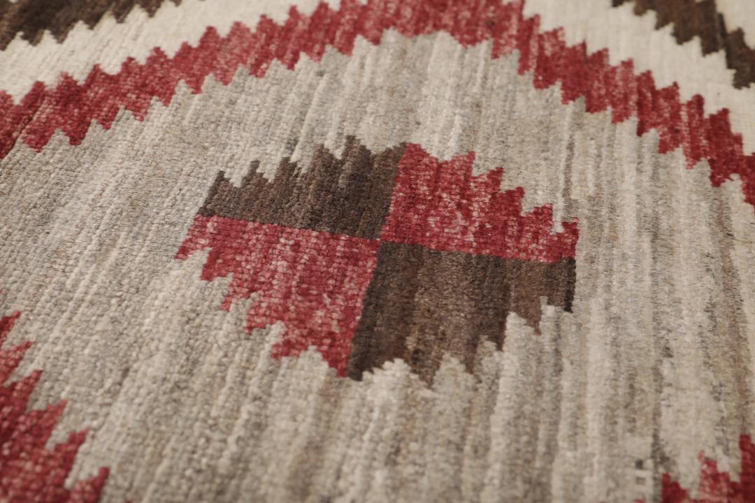 Een handgeknoopte Afghaanse loper met een gedurfd geometrisch ruitpatroon in rode, bruine en beige tinten.