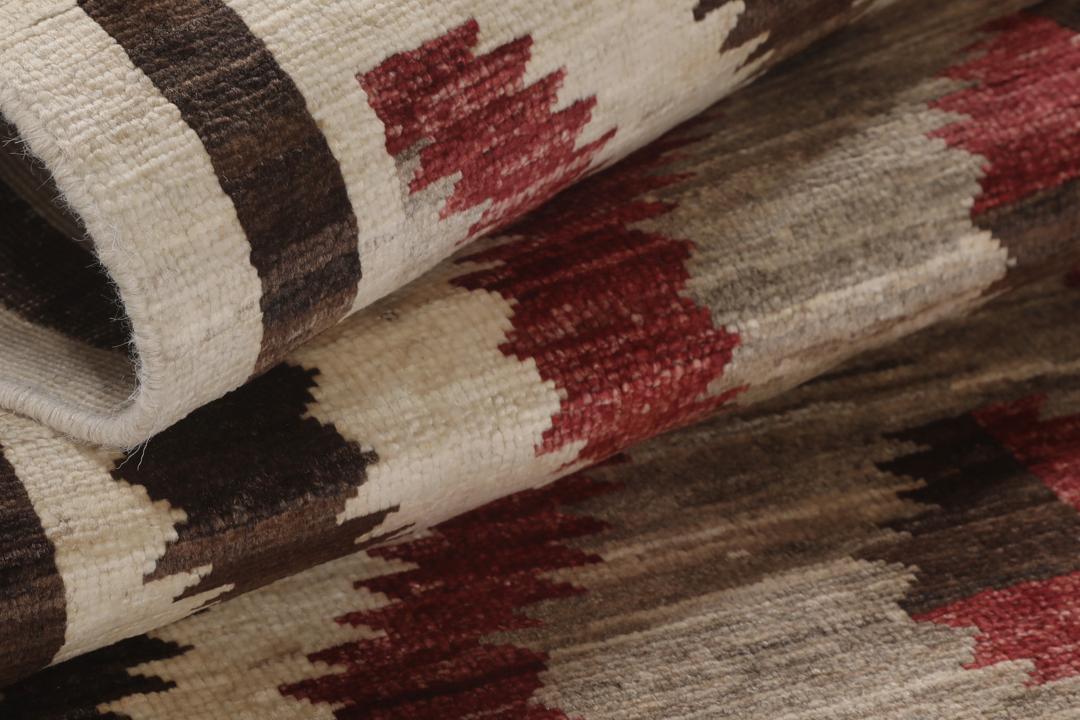 Een handgeknoopte Afghaanse loper met een gedurfd geometrisch ruitpatroon in rode, bruine en beige tinten.