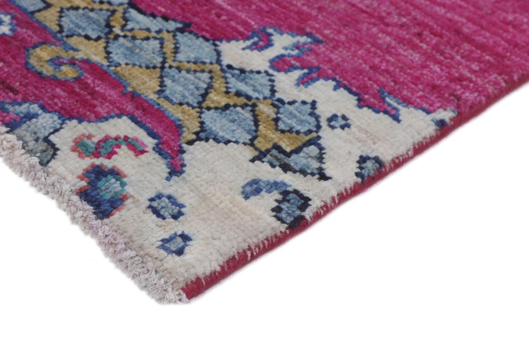 Un tapis afghan vibrant avec des motifs figuratifs dans des tons roses et bleus.