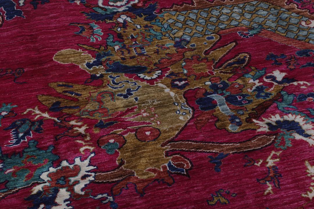 Un tapis afghan vibrant avec des motifs figuratifs dans des tons roses et bleus.