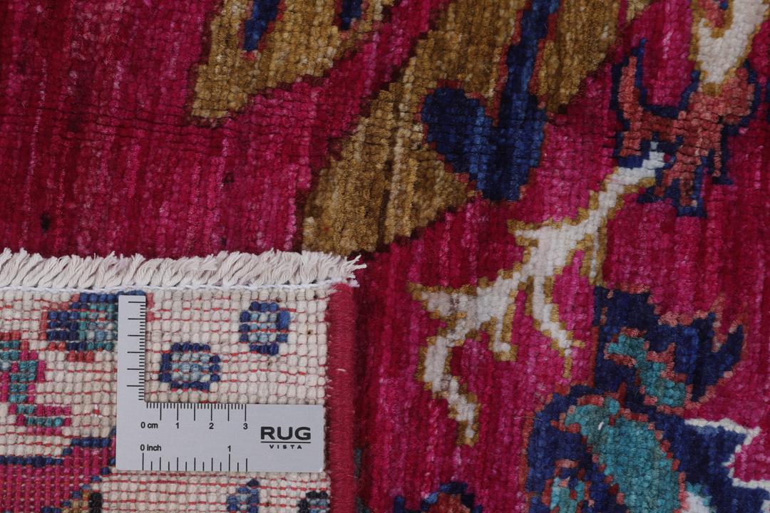 Un tapis afghan vibrant avec des motifs figuratifs dans des tons roses et bleus.