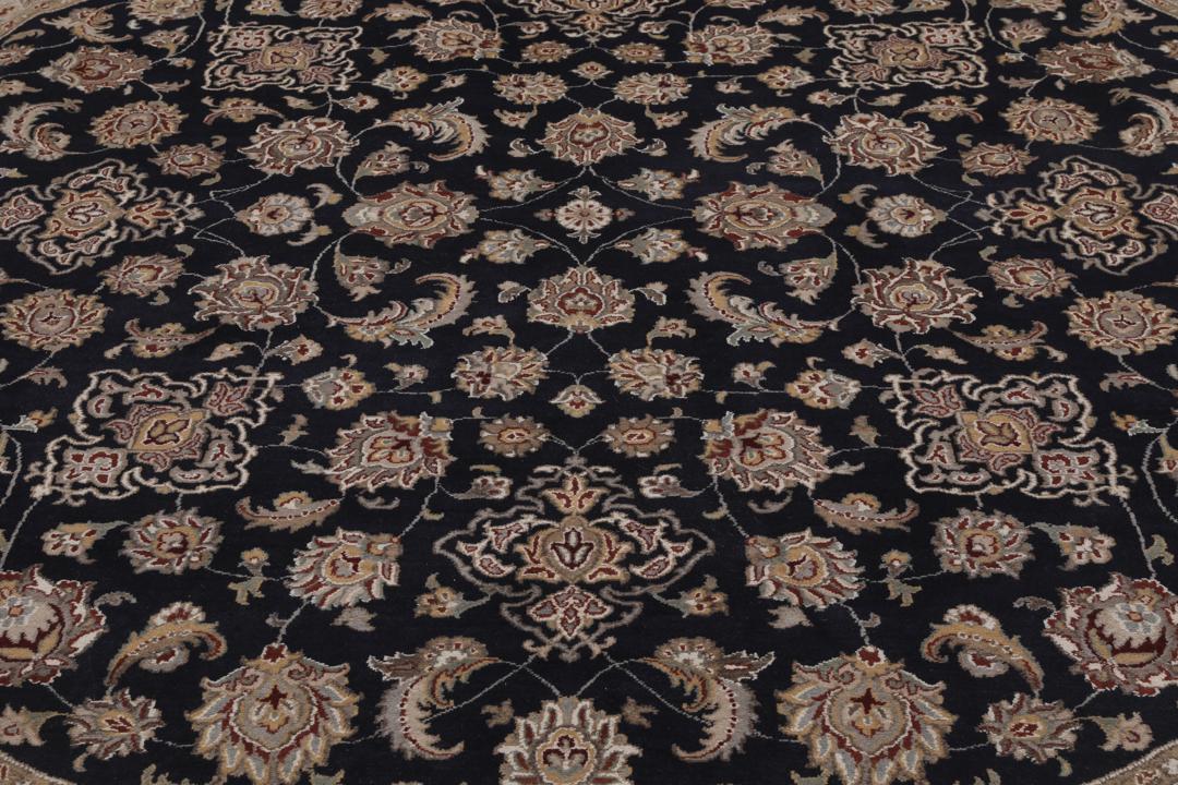 Et rundt Tabriz-tæppe med en dybblå midte og en detaljeret blomsterkant fra Indien.