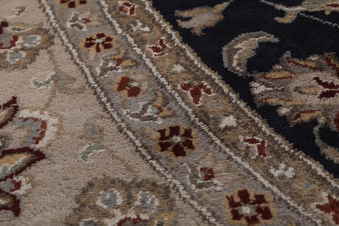 Et rundt Tabriz-tæppe med en dybblå midte og en detaljeret blomsterkant fra Indien.