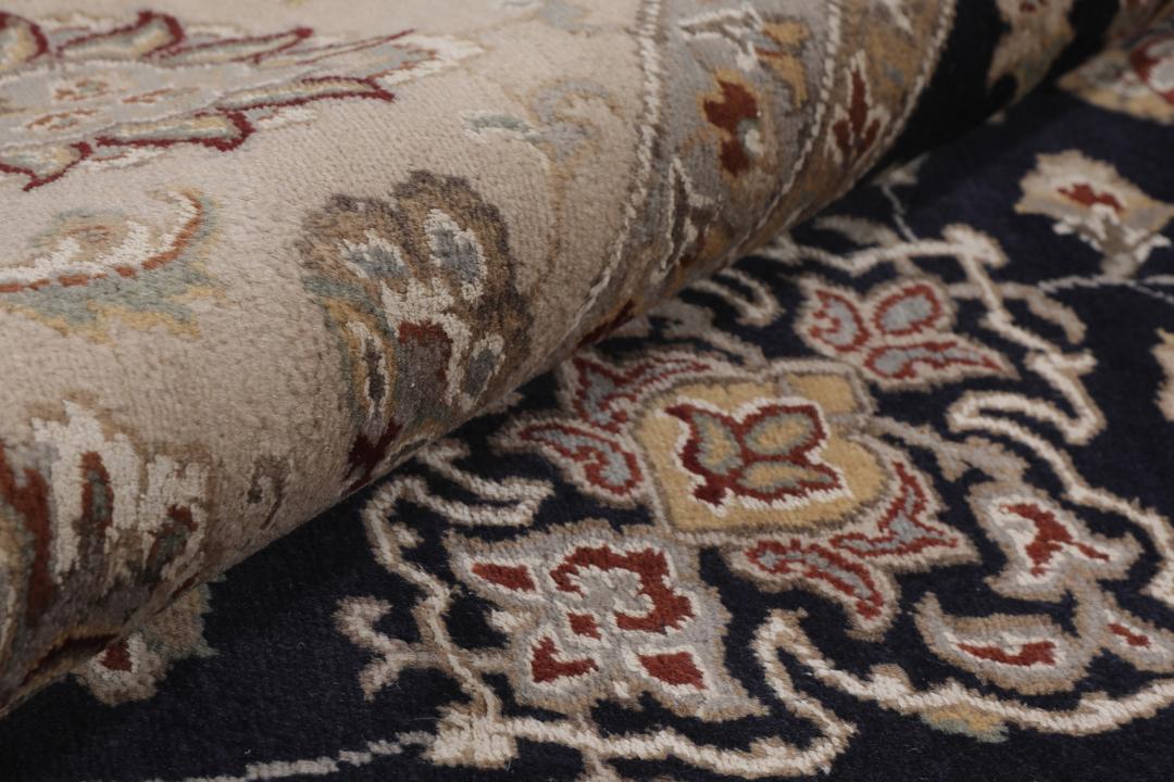 Et rundt Tabriz-tæppe med en dybblå midte og en detaljeret blomsterkant fra Indien.
