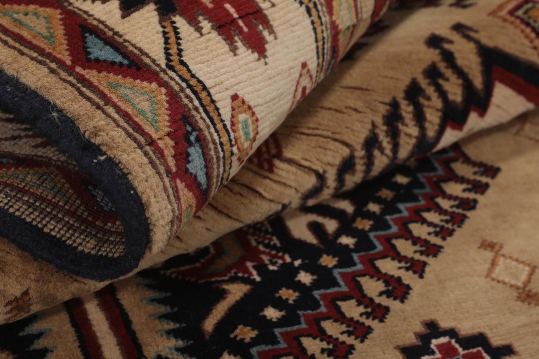Håndknyttet afghansk tæppe i beige med traditionelle geometriske mønstre og medaljoner.