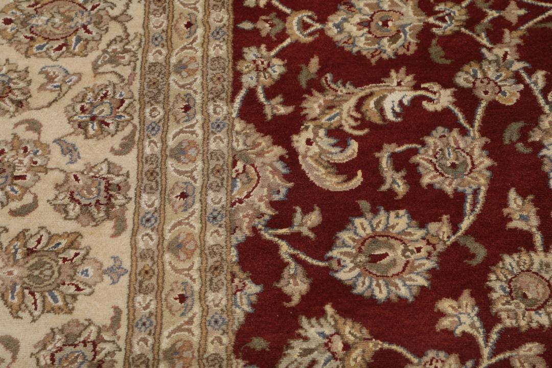 Ręcznie wiązany dywan Tabriz z Indii z czerwonym tłem i misternymi kremowymi wzorami kwiatowymi.