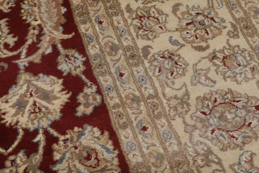 Ręcznie wiązany dywan Tabriz z Indii z czerwonym tłem i misternymi kremowymi wzorami kwiatowymi.