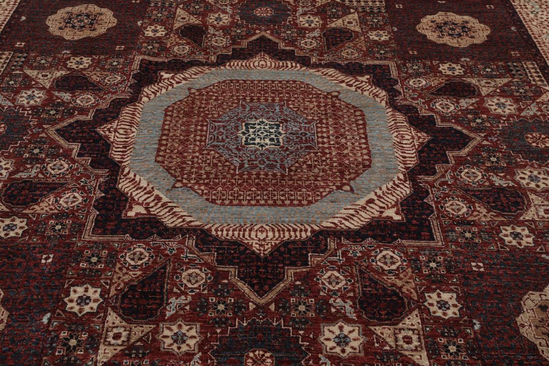 Et håndknyttet Mamluk-tæppe fra Afghanistan i røde og beige nuancer.