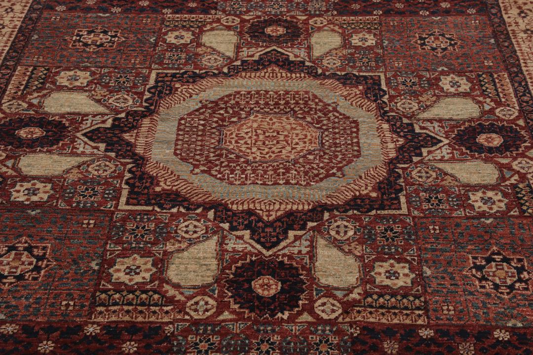 Et håndknyttet afghansk Mamluk-tæppe i rød og beige med geometriske medaljonmønstre.