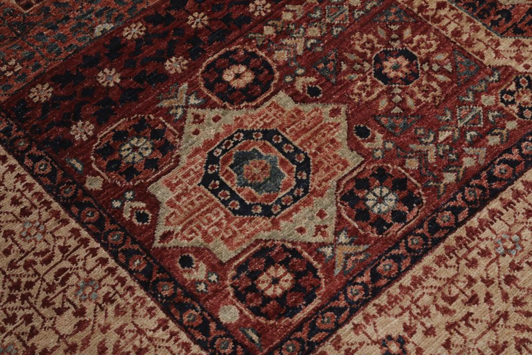 Et håndknyttet afghansk Mamluk-tæppe i rød og beige med geometriske medaljonmønstre.