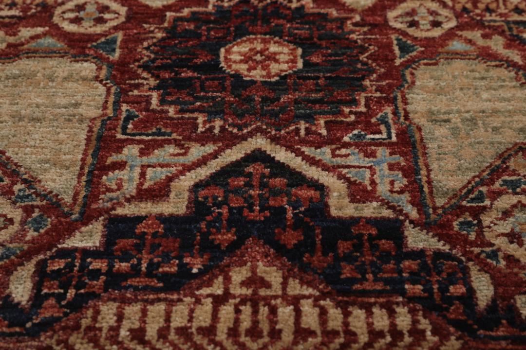 Et håndknyttet afghansk Mamluk-tæppe i rød og beige med geometriske medaljonmønstre.