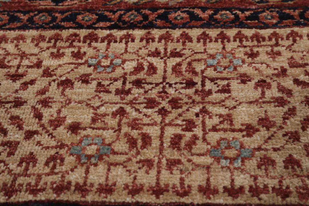 Et håndknyttet afghansk Mamluk-tæppe i rød og beige med geometriske medaljonmønstre.