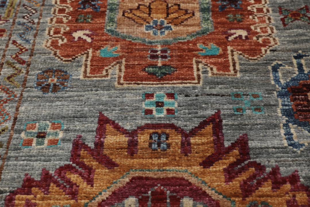 Alfombra de lana anudada a mano procedente de Afganistán con intrincados motivos multicolor sobre un fondo gris.