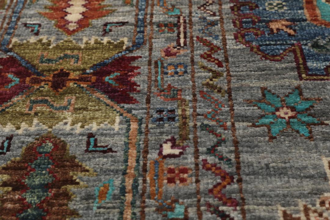 Alfombra de lana anudada a mano procedente de Afganistán con intrincados motivos multicolor sobre un fondo gris.