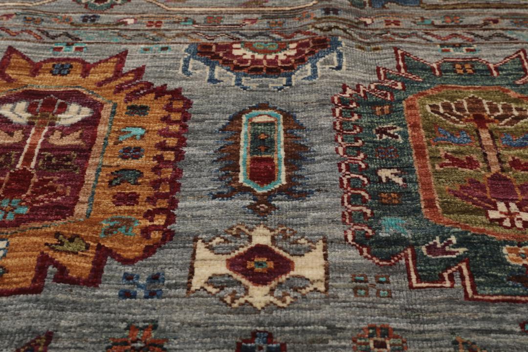 Alfombra de lana anudada a mano procedente de Afganistán con intrincados motivos multicolor sobre un fondo gris.