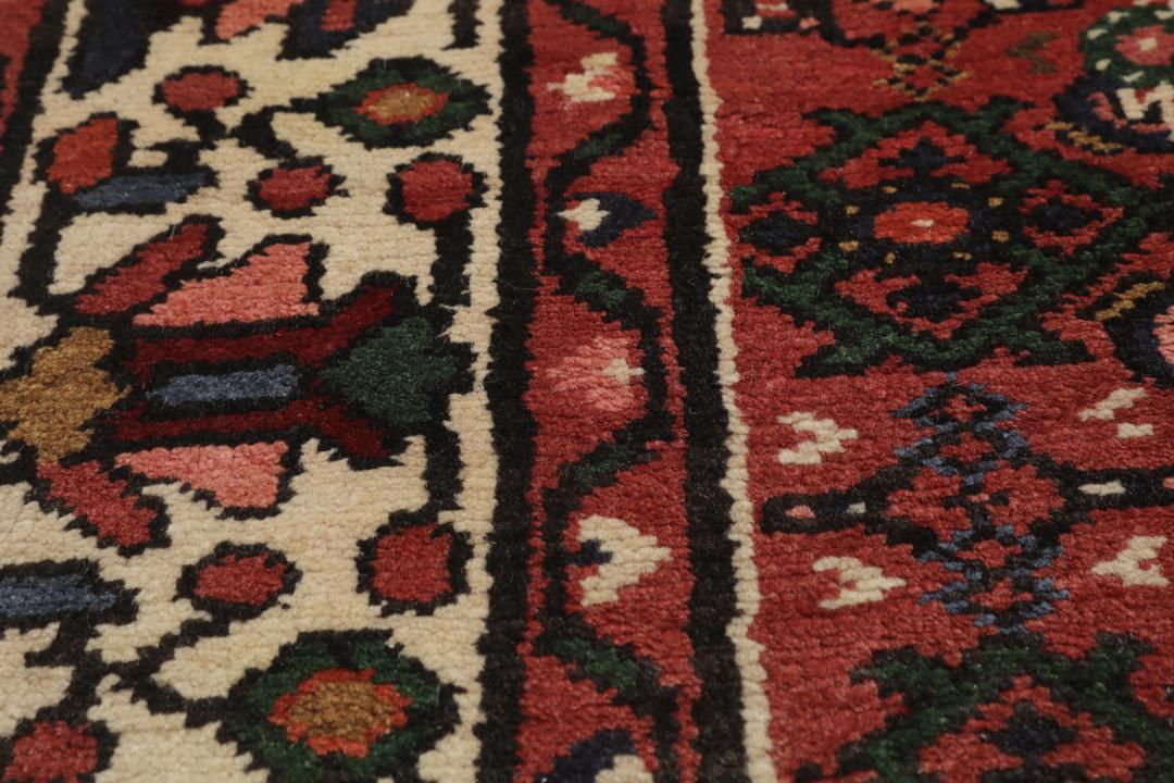 Et håndknyttet Hosseinabad-tæppe fra Mellemøsten i dybe mørkerøde toner.