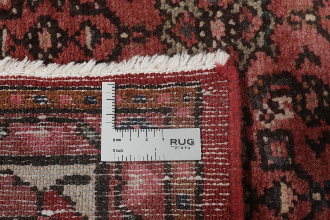 Et håndknyttet Hosseinabad-tæppe fra Mellemøsten med et mørkerødt felt.