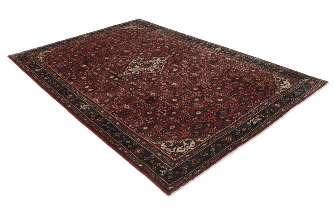 A large hand-knotted Hosseinabad rug from the Middle East featuring red and dark blue tones.