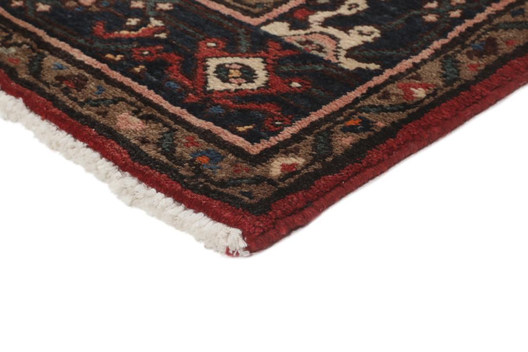A large hand-knotted Hosseinabad rug from the Middle East featuring red and dark blue tones.