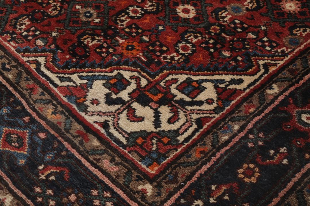 A large hand-knotted Hosseinabad rug from the Middle East featuring red and dark blue tones.