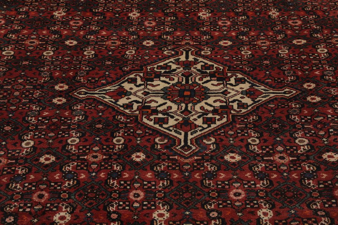 A large hand-knotted Hosseinabad rug from the Middle East featuring red and dark blue tones.