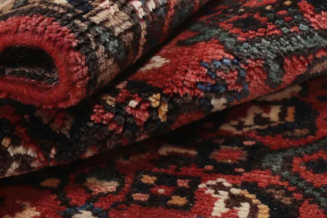 A large hand-knotted Hosseinabad rug from the Middle East featuring red and dark blue tones.