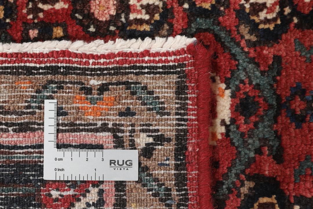 A large hand-knotted Hosseinabad rug from the Middle East featuring red and dark blue tones.