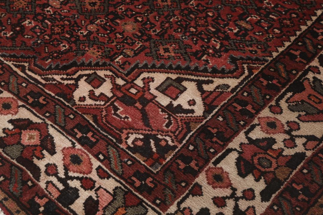 Een handgeknoopt Hosseinabad-tapijt uit het Midden-Oosten in diepe donkerrode tinten.