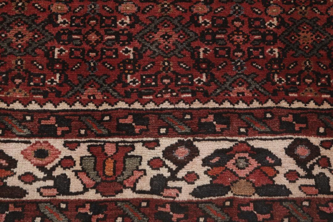 Een handgeknoopt Hosseinabad-tapijt uit het Midden-Oosten in diepe donkerrode tinten.