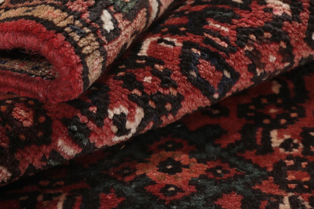 Een handgeknoopt Hosseinabad-tapijt uit het Midden-Oosten in diepe donkerrode tinten.