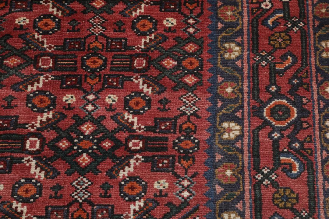 Hand-knotted Hosseinabad rug with red and dark-blue tones from the Middle East.
