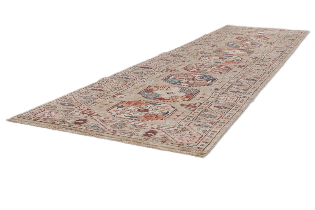 Una alfombra pasillera afgana anudada a mano con tonos beige y motivos de medallones.