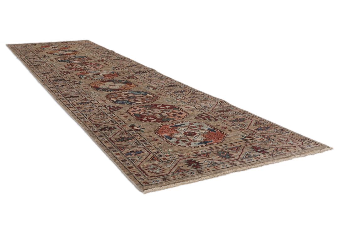 Una alfombra pasillera afgana anudada a mano con tonos beige y motivos de medallones.
