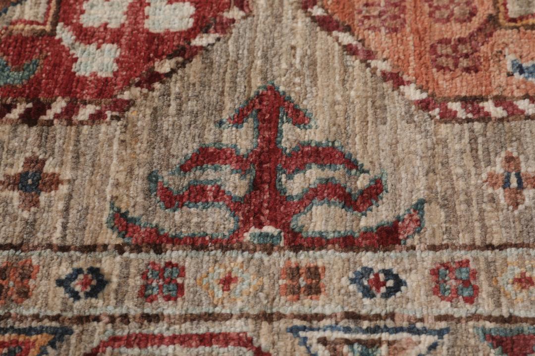 Una alfombra pasillera afgana anudada a mano con tonos beige y motivos de medallones.