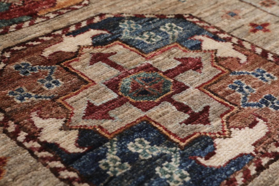 Una alfombra pasillera afgana anudada a mano con tonos beige y motivos de medallones.