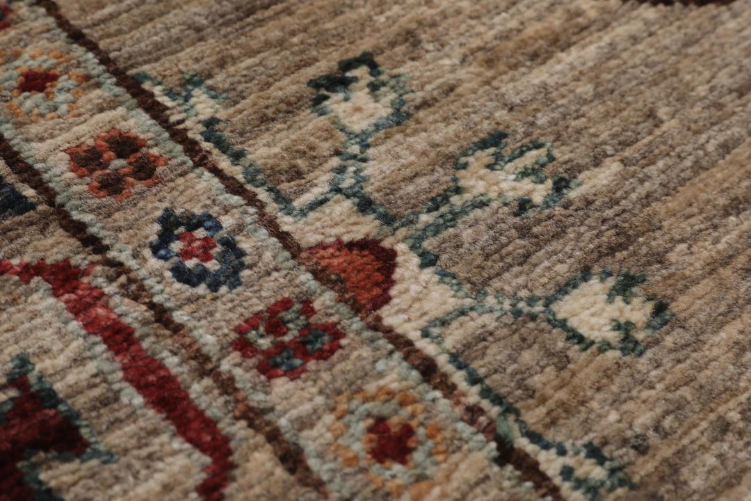Una alfombra pasillera afgana anudada a mano con tonos beige y motivos de medallones.