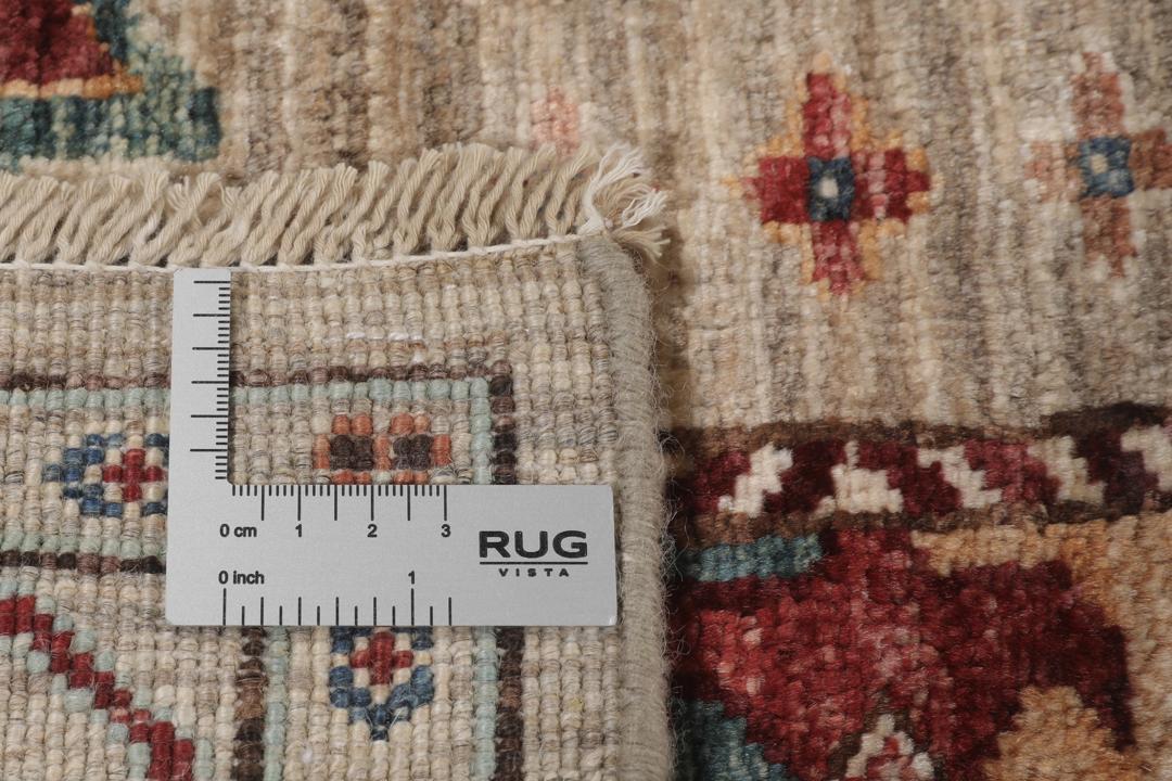 Una alfombra pasillera afgana anudada a mano con tonos beige y motivos de medallones.