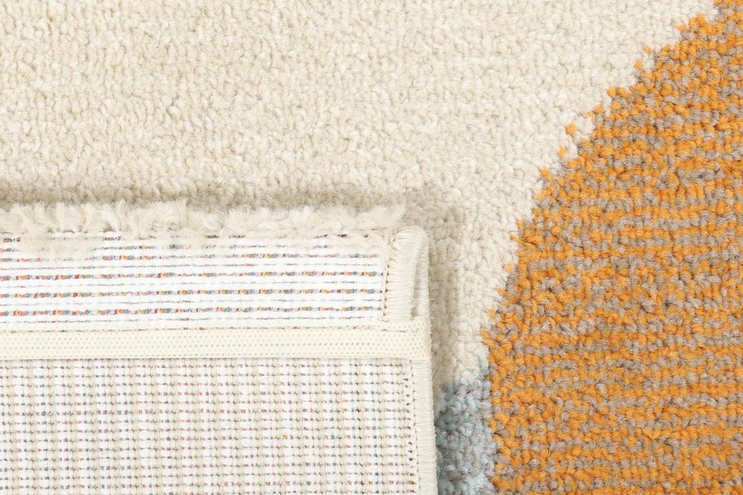 Beige tæppe med et legende flerfarvet fiskemønster.