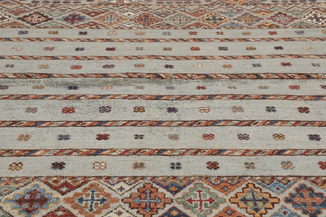 Una alfombra rectangular anudada a mano de Afganistán con una base verde y patrones geométricos