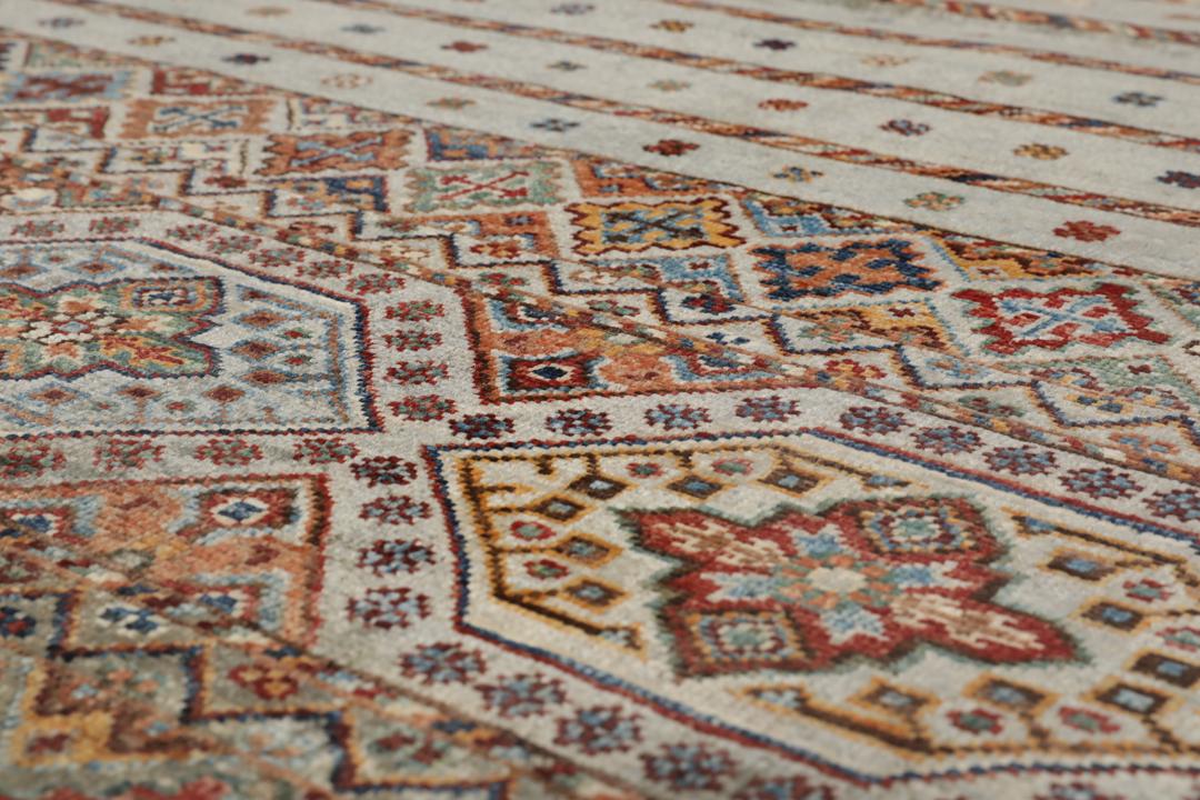 Una alfombra rectangular anudada a mano de Afganistán con una base verde y patrones geométricos