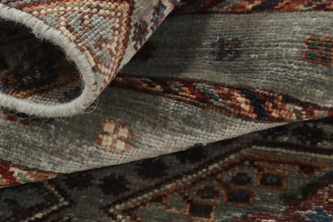 Una alfombra rectangular anudada a mano de Afganistán con una base verde y patrones geométricos