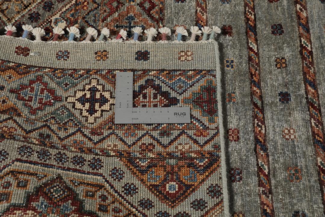 Una alfombra rectangular anudada a mano de Afganistán con una base verde y patrones geométricos
